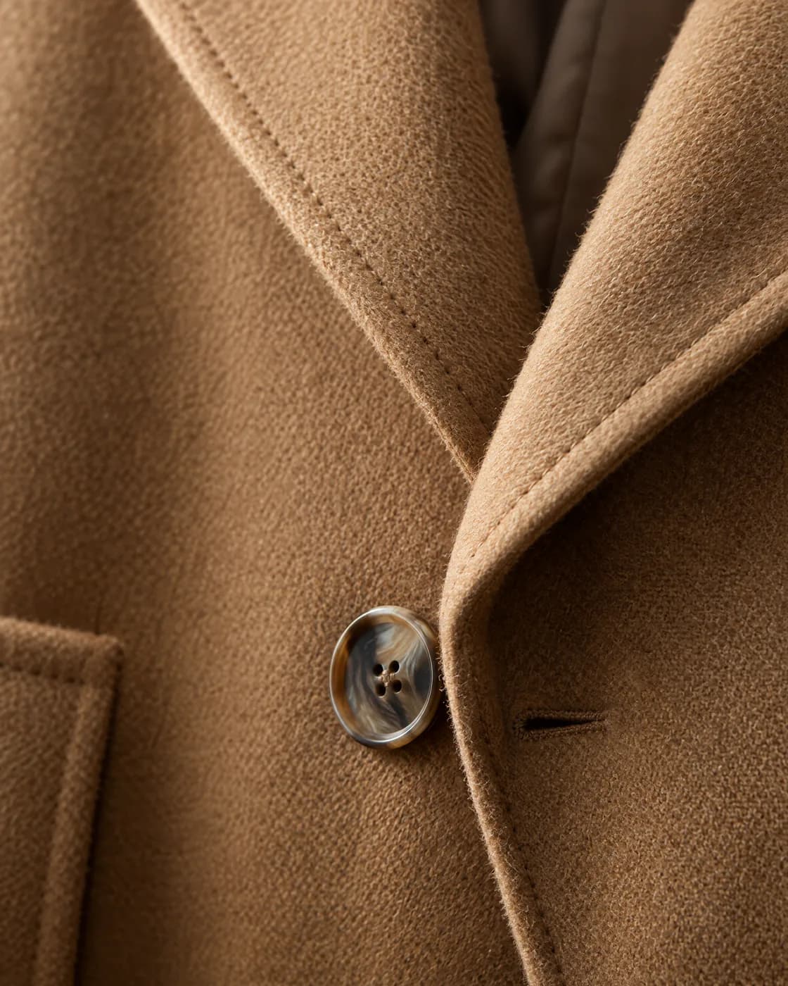 Détail du manteau camel : tissage de la laine, bouton en corne et surpiqûres du revers