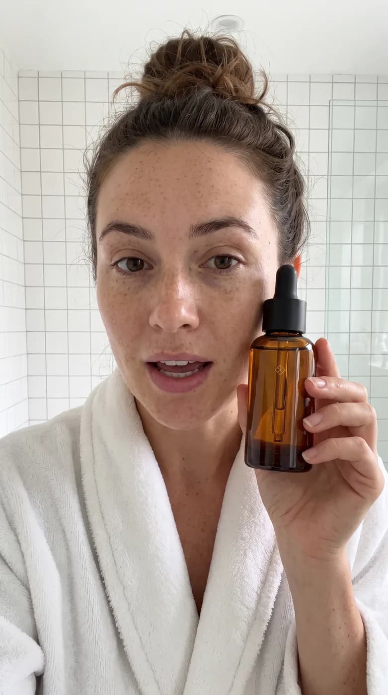 Vidéo verticale de style UGC : une femme dans sa salle de bain présente le flacon de sérum ambré face caméra